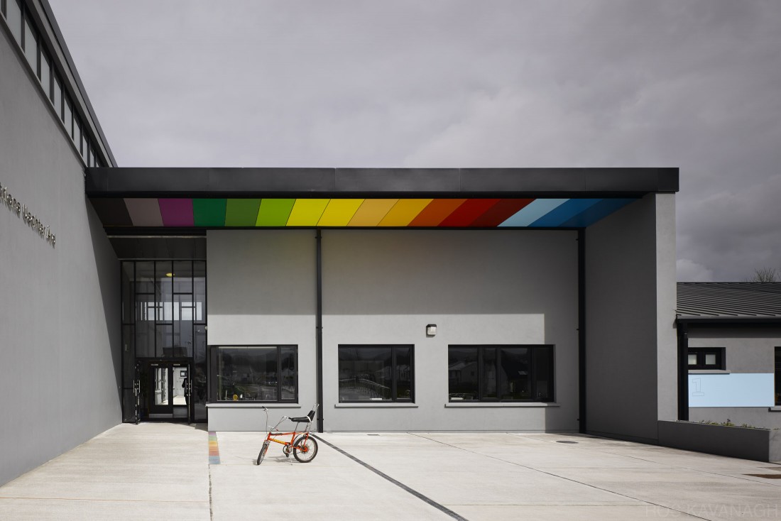 Wide view of school entrance showing coloured soffit panels and bicycle