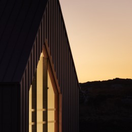 Exterior facade at dusk showing roof pitch and interior lights